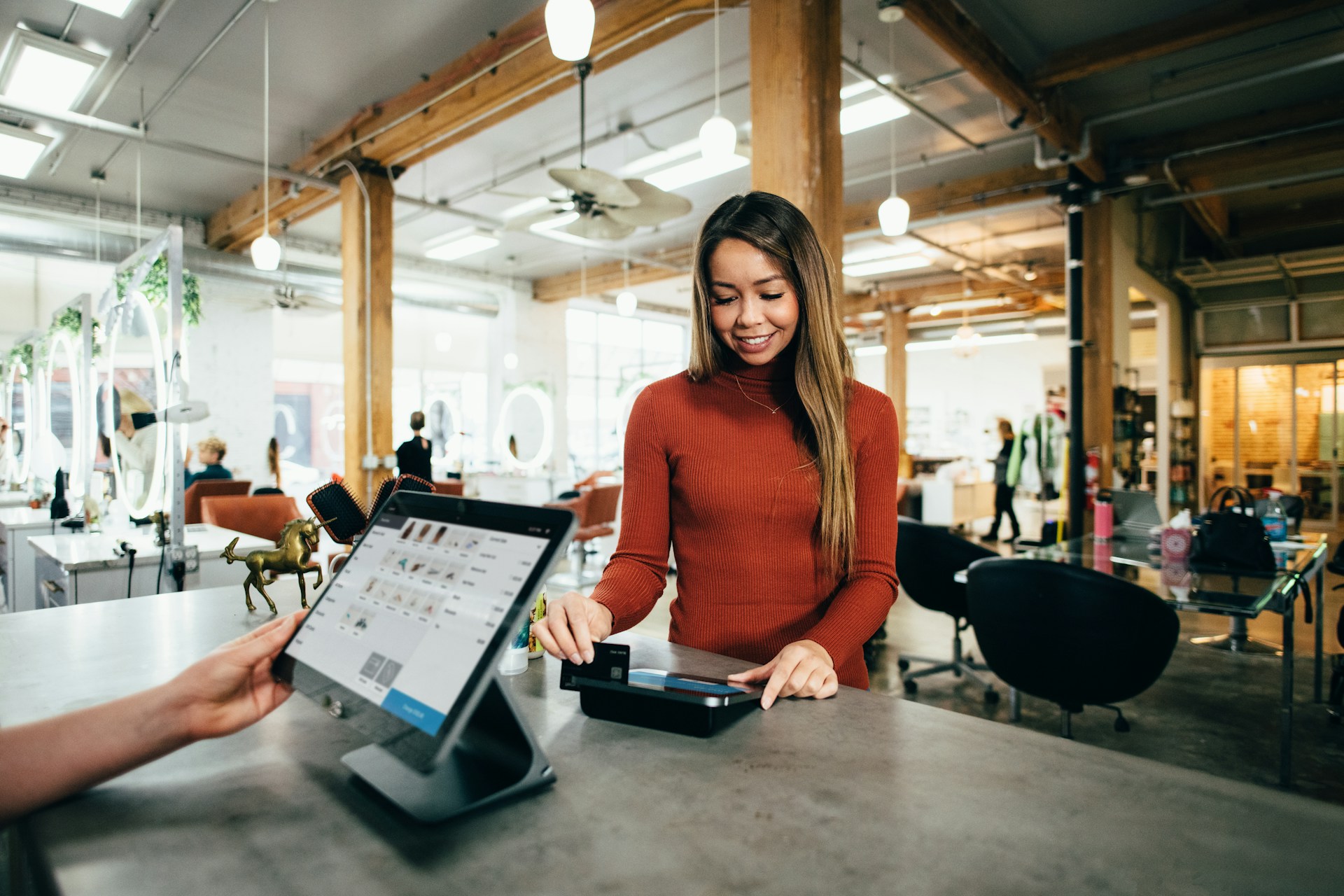 Image of a woman using her credit card to make a purchase at a point of sale.